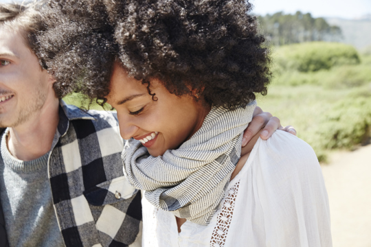 A man and woman share a joyful moment, smiling and gazing into each other's eyes with warmth and affection.