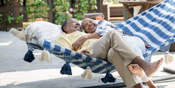 an elderly couple rests in each other's arms on a swing