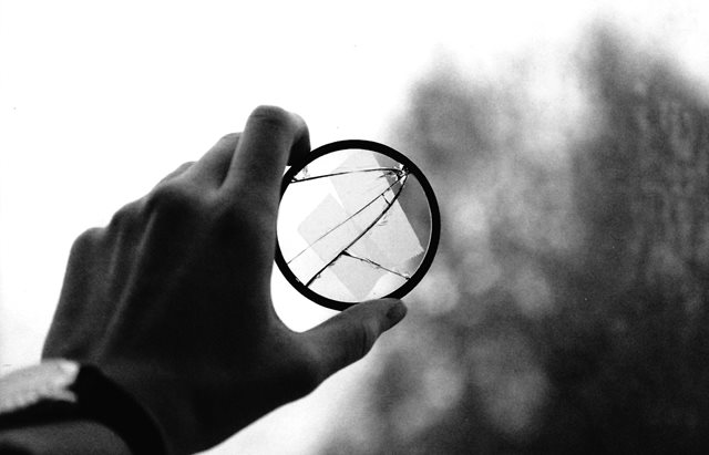 hand holding a broken magnifying glass