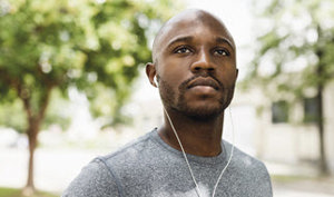 A man wearing earbuds and headphones, immersed in music, with a focused expression on his face.