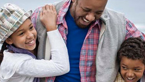 A heartfelt hug shared between a man and two children, symbolizing love and connection.