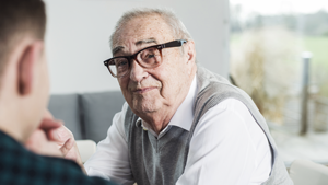 An elderly man with spectacles is positioned next to a younger man