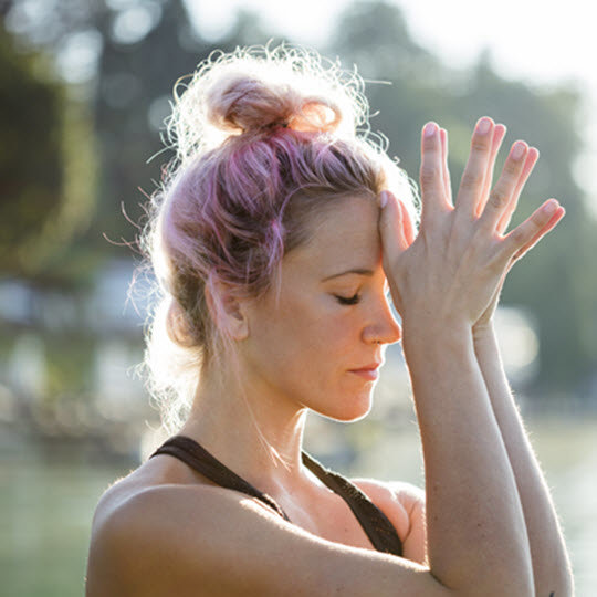 A woman with pink hair practicing yoga in a serene environment, showcasing flexibility and focus.